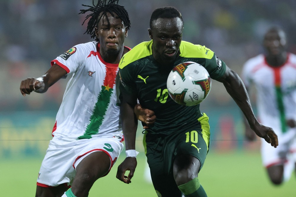 Pemain depan Senegal Sadio Mane (kanan) berusaha melewati Bek Burkina Faso Issa Kabore selama pertandingan sepak bola semi final Piala Afrika  2021. AFP/ Kenzo Tribouillard